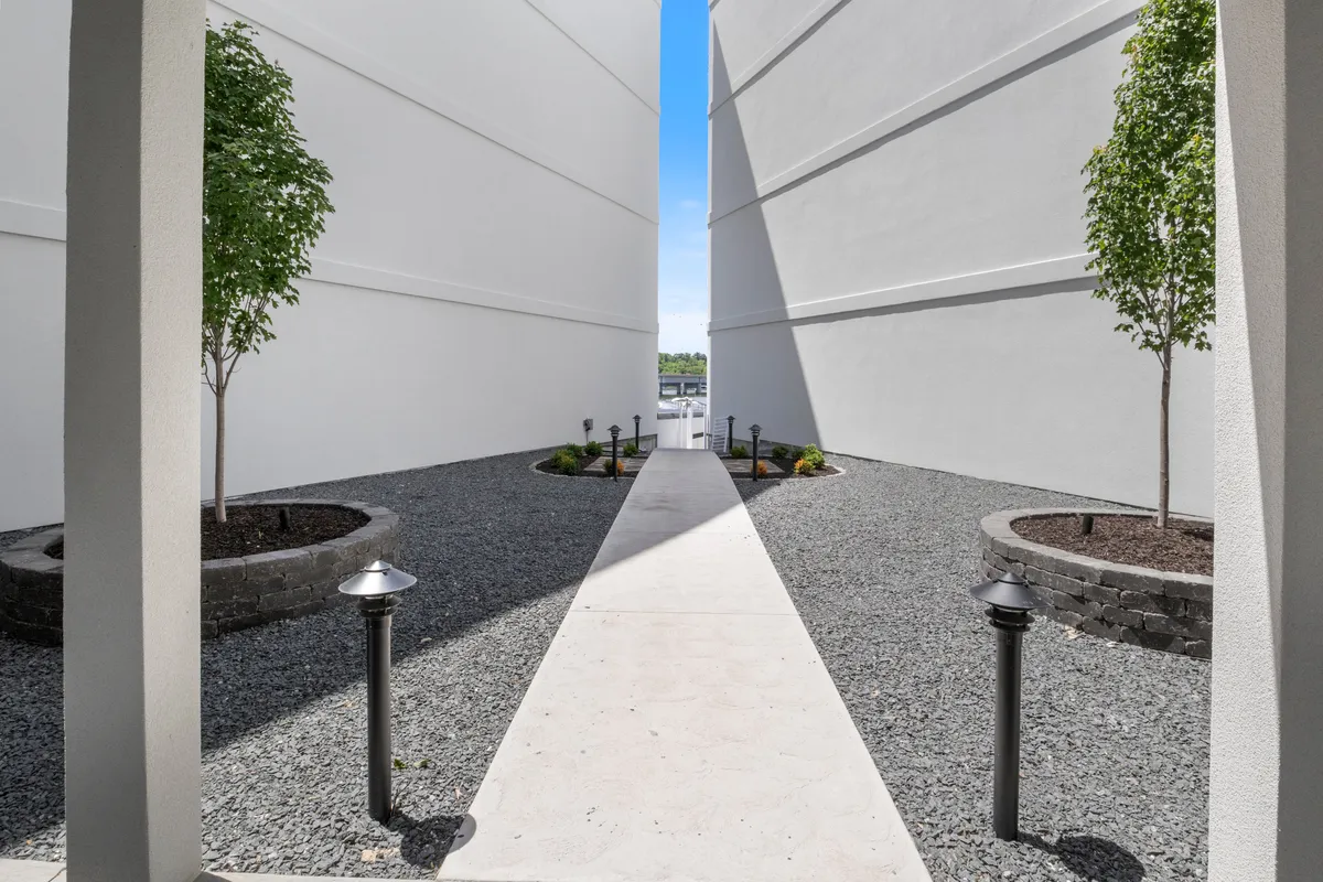 A winding pathway is bordered by trees and soft lighting, creating a peaceful, welcoming environment. The landscaped garden encourages leisurely strolls and moments of reflection, echoing the tranquil lakeside setting described in the section.