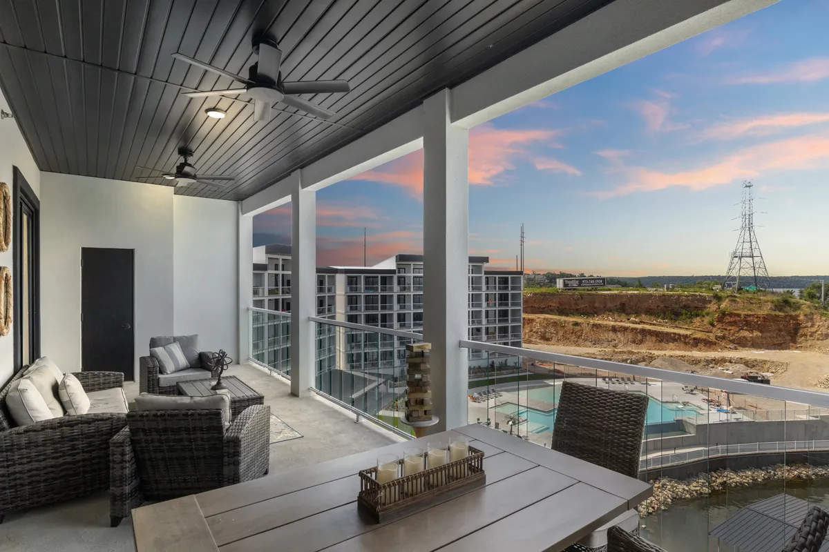 An inviting exterior scene showing an outdoor seating and dining area on a balcony, overlooking a serene sunset with the pool area below. The image conveys a sense of tranquility and togetherness, highlighting opportunities for outdoor meals and gatherings against a beautiful backdrop.