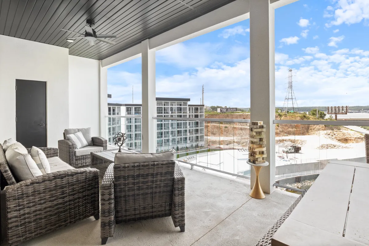 This image captures an outdoor seating area on a balcony, with views overlooking the lake. The scene is tranquil, with comfortable chairs arranged to enjoy the natural surroundings and a decorative sculpture adding an upscale touch. The atmosphere is serene, ideal for enjoying morning coffee or evening relaxation with a loved one or a small group.