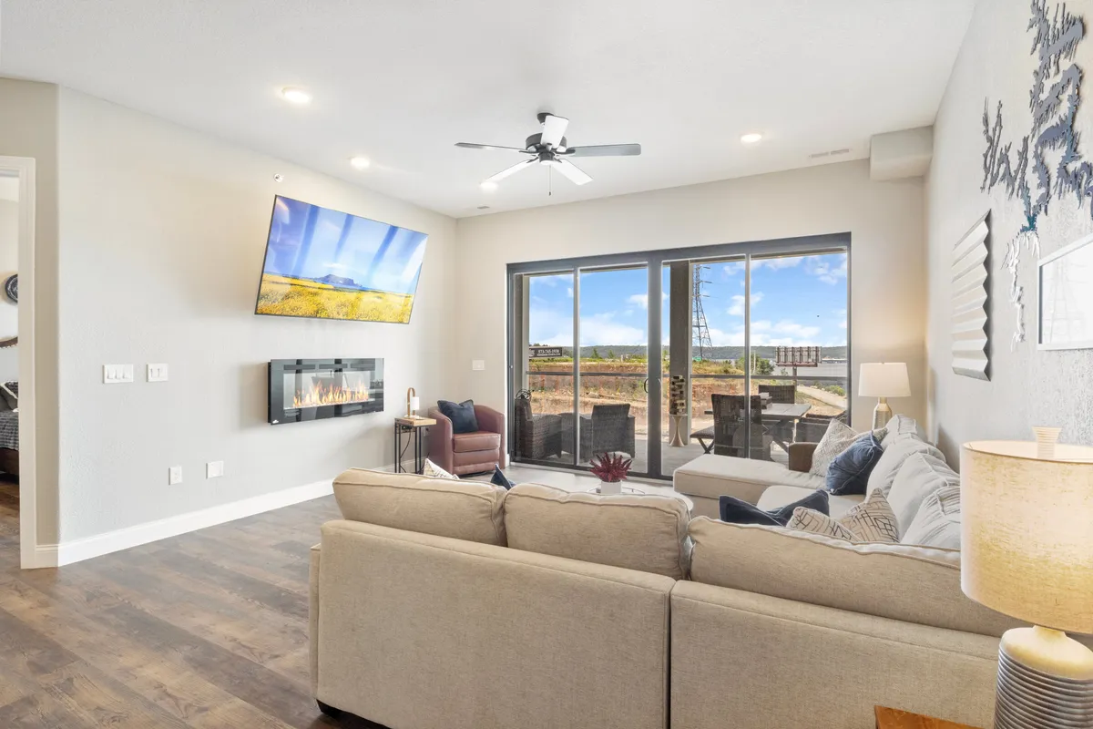 A warm, inviting living area with a modern fireplace, expansive windows looking out onto the landscape, a comfortable sofa, and a wall-mounted TV. The ambiance is both cozy and secure, suggesting a blend of private retreat and thoughtful design.