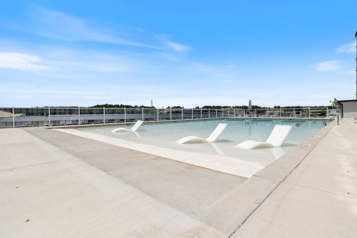 An inviting exterior view of a sparkling pool lined with comfortable lounge chairs, set under an open sky. The pool area appears peaceful and well-maintained, perfect for relaxation, sunbathing, or socializing after a day of exploring local attractions.