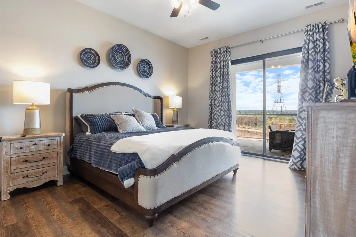 A spacious bedroom with a large bed, decorative pillows, and nightstands with lamps. A sliding glass door opens directly to a patio, allowing guests to enjoy fresh air and natural light. The room exudes serenity and comfort—perfect for a private getaway.